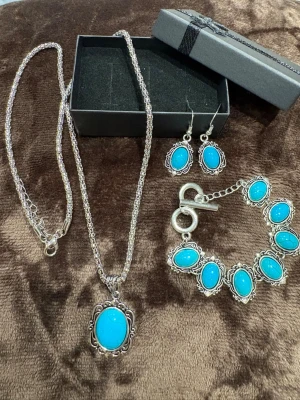 Turkos väst med silverdetaljer - Säljer en snygg väst med turkosa stenar och silverfärgad ram. Västen har en klassisk form med dekorativa detaljer som ger en cool och unik look. Perfekt för dig som vill sticka ut och addera färg till din outfit.