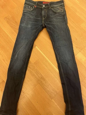 Replay Jondrill slim jeans blå - Säljer ett par Replay Jondrill jeans i mörkblå tvätt med skinny passform. Klassiska femficksdetaljer, snygga kontrastsömmar och Replay-logga på bakfickan. Jeansen har låg midja och är tillverkade i stretchig jeansmaterial för extra komfort.