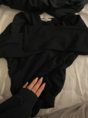 Svart långärmad tröja med dragkedja - Säljer en svart långärmad tröja med dragkedja i sidan. Tröjan har en enkel och clean look, perfekt till alla outfits. Materialet känns rikt. Passformen är väldigt figursydd och tröjan är utan synliga mönster eller detaljer.