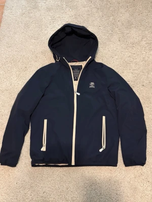 Mörkblå dunjacka med huva från Brunello Cucinelli - Väldigt bekväm och isolerande dunjacka från Brunello Cucinelli som endast använts ett fåtal gånger. Ungefärligt nypris var 2800 euro. Inga kvitton kvar. Välkomnar seriösa och lämpliga prisförslag.