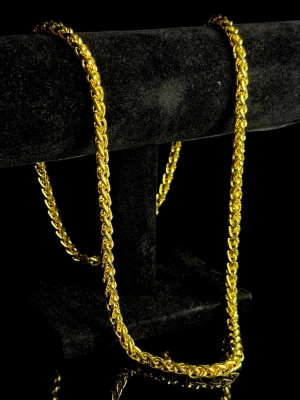 Golden Revenue Rope Chain - Golden Revenue Rope Chain är en kraftfull halskedja i klassisk repankarlänk (rope chain) med glänsande guldfinish. Den täta, tvinnade flätningen ger ett exklusivt uttryck och reflekterar ljus på ett sätt som verkligen drar blickarna till sig. Kedjan har bra tyngd och solid känsla, vilket ger ett premiumintryck när den bärs – inget lätt eller tunt smycke. Perfekt som accessoar, både till vardags och fest, och lika snygg att bära ensam som tillsammans med andra kedjor. Helt ny. Box medföljer!