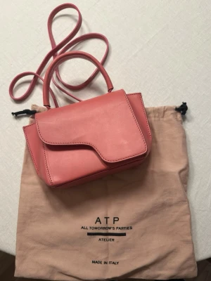 Rosa axelväska från ATP Atelier - Snygg rosa axelväska från ATP Atelier med stilren design och asymmetrisk lockstängning. Slitningar finns och syns på bilderna.