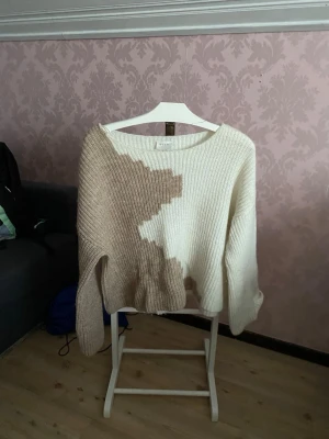 Beige och vit stickad coldshoulder  - Supermysig stickad tröja från Vila i storlek S. Tröjan har ett coolt mönster i beige och vitt, med breda ribbstickade partier och en snettskuren krage för en avslappnad passform som blir jättefin likande”cold shoulder”. Perfekt för under kyliga dagar som man ändå vill känna sig lite piffig.✨