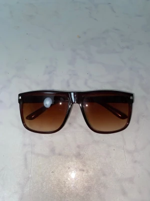 Bruna faded solglasögon - Säljer ett par bruna faded solglasögon med en clean look. Perfekt för sommaren och mot att skydda ögonen mot heta solstrålar.