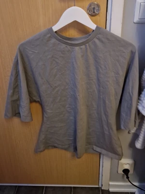 Grön t-shirt från 157 - En basic grön t-shirt från 157. T-shirten har klassisk rund hals och korta ärmar, den är utsvängd längst ner. Perfekt för en chill och enkel stil. Materialet känns mjukt och skönt mot huden, och färgen är lätt att matcha med det mesta.