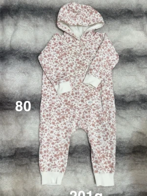 Blommig byxdress med huva, storlek 80 - Säljer en söt byxdress från Newbie i storlek 80, med blommigt mönster i rosa och vitt. Dressen har huva, långa ärmar och vita muddar vid ärmslut och benslut. Perfekt för mysiga dagar hemma eller när du vill vara extra bekväm.🌸 Inte använd många gånger men lyckats få ljusgula fläckar/missfärgning. Storlek 80