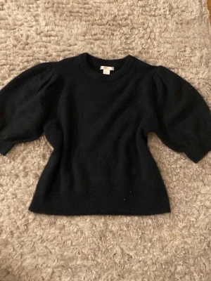 Svart stickad tröja Gina Tricot - Lite svårt att se men det är mörkblå Mysig stickad tröja från Gina Tricot med puffiga korta ärmar och rund hals. Perfekt till höst och vinter när du vill ha något enkelt men ändå snyggt. Knappt använd och väldigt mjuk 