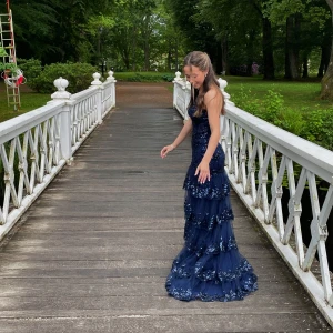 Marinblå balklänning - Säljer en marinblå långklänning med paljetter och volanger. Klänningen har oneshoulder-modell, slits framtill och är täckt av glittriga detaljer och inbyggd BH. Perfekt för bal eller student. Bekväm att bära!😊