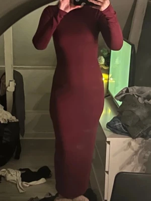 Vinröd långklänning från Bik Bok - Säljer en vinröd långklänning från Bik Bok i storlek XS. Klänningen har en figurnära passform, rund halsringning och långa ärmar. Materialet är mjukt och stretchigt, vilket gör den bekväm att bära. Perfekt för dig som gillar stilrena och enkla plagg med snygg siluett.