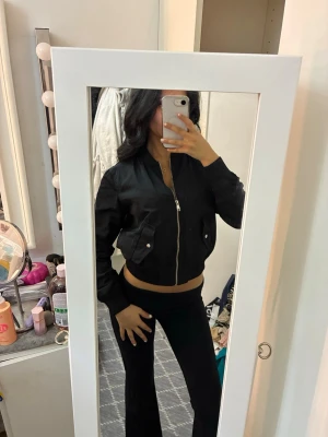 Svart bomberjacka med dragkedja - Säljer en svart bomberjacka med silvrig dragkedja och två fickor med knappstängning framtill. 