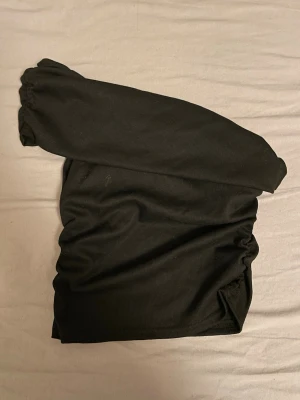 Svart topp  - Säljer en svart topp med rynkade detaljer på sidorna. Toppen har en enkel och stilren design, perfekt att matcha med jeans eller kjol. Materialet känns mjukt och stretchigt, vilket gör den bekväm att bära hela dagen.