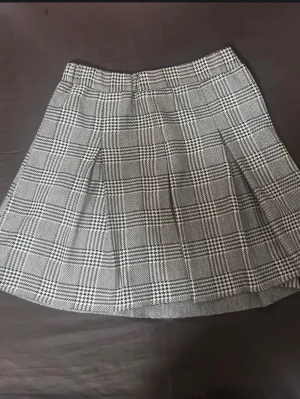 Grå rutig kortkjol med veck - Grå och vit rutig kortkjol med klassiskt rutmönster och veck