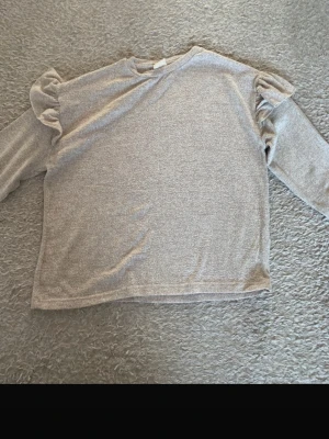 Beige tröja med volang från Zara Kids - Säljer en beige långärmad tröja från Zara Kids i storlek 134. Tröjan har snygga volangdetaljer på axlarna och är gjord i mjukt bomullsmaterial. Perfekt för dig som gillar stilrena plagg med en twist. Passar dig som vill ha något enkelt men ändå lite extra.