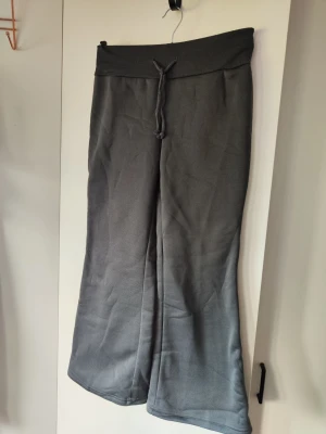 Mörkgrå mjukisbyxor med snörning - Helt nya! Mörkgrå mjukisbyxor med bred resår i midjan och snörning framtill. Byxorna har en loose passform med raka, lite vidare ben och är fodrade med mjuk fleece på insidan. Perfekta för chill och mysiga dagar. Benlängden mäter ca 64 cm från grenen. Midjemått 35cm och kan streckas ut till 45cm. 