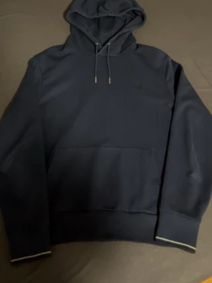 Fred perry hoodie - Mörkblå fred perry hoodie som jag har haft på mig några gånger och är inprincip ny med inga fel på.