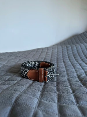 Svartvit flätad bälte  - Tja den är helt nytt längd 105cm och bred 3,5cm från BÄLTGALLERIAN