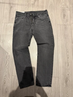 Svarta regular fit jeans från H&M - Svarta jeans från H&M med regular fit och klassisk femficksdesign. Jeansen har rak passform och är tillverkade i ett slitstarkt bomullsmaterial. Perfekt för dig som gillar en enkel och stilren look. Storlek 32/32.