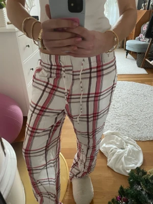 Rutig mjukisbyxa med snörning - Säljer ett par chill rutiga mjukisbyxor i vitt med röda och svarta ränder. De har en skön loose passform och snörning i midjan för extra komfort. Så himla snygga, som nya!! 💘💘storlek xs!