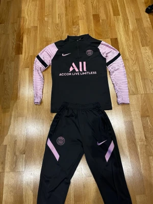 PSG Nike tracksuit  - Säljer ett svart och rosa träningsset från PSG och Nike med stretchigt material. Kan användas som varje dag kläder men även som sportkläder/Träningskläder 