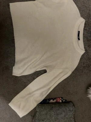 Vit stickad tröja från 157 - Säljer en enkel och stilren vit stickad tröja från 157 i storlek S. Tröjan har rund hals, långa ärmar och ribbade muddar vid hals, ärmslut och nederkant. Perfekt för lager-på-lager under kyliga dagar.