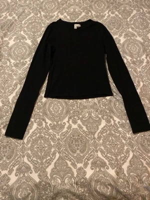 Svart långärmad topp H&M Divided XS - En enkel och stilren svart långärmad topp från H&M Divided i storlek XS. Modellen är croppad med rund halsringning och har en tight passform. 