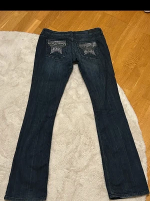 Mörkblå jeans med stjärndetaljer Amisu - Säljer ett par mörkblå jeans från Amisu med raka ben och snygga stjärnor i paljetter på bakfickorna.  Jeansen är low waist bootcut.