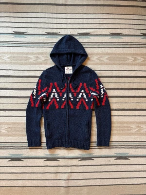 Stickad blå zip hoodie från hollister - Sjukt snygg o eftertraktad zip hoodie från hollister. Den är blå med rött o vitt mönster. Storlek S!