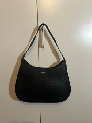 Svart axelväska från Calvin Klein - Väska i gott skick. Köpt för 1699kr. Kvitto finns. 23x36x5 