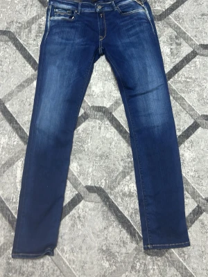 Replay - Snygga blå jeans med raka ben och klassisk femficksdesign. Jeansen har en mörkblå tvätt med lätt slitning framtill och kontrastsömmar. Perfekta till vardagslooken och tillverkade i mjukt bomullsmaterial för skön passform.