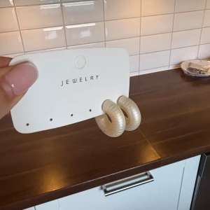 Chunky pärlemor hoops örhängen -  hoops örhängen i pärlemorskimrande plast. De har en rund, tjock form och ger ett trendigt statement till din look. Perfekta för dig som gillar att sticka ut med accessoarerna.