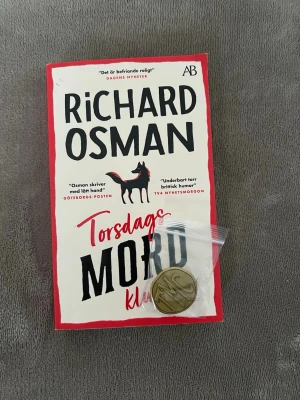 Torsdagsmordklubben TMC-mynt - Säljer nålmärke från 'Torsdagsmordklubben' av Richard Osman och Netflix. Den är en oval metallpin med TMC-initialer i guldton, förpackad i plastpåse. Perfekt för dig som gillar deckare med humoristisk twist. Boken ingår ej. Exklusivt distribuerad på specifika platser i Storbritannien. Nålversion av halsbanden som de fyra i filmen har. 3cm i diameter.