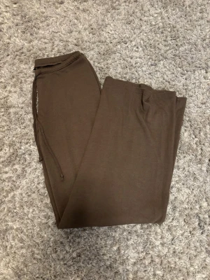 Bruna mjukisbyxor från Nelly - Mysiga bruna mjukisbyxor från Nelly med dragsko i midjan. Byxorna har en enkel och stilren design, perfekta för chill dagar hemma eller när du vill vara bekväm. Tillverkade i mjukt material som känns skönt mot huden. Sista bilden ser man hur de ser ut på. Jag är ca 173 och de är lite korta på mig. Lite noppriga på rumpan, men annars fint skick.