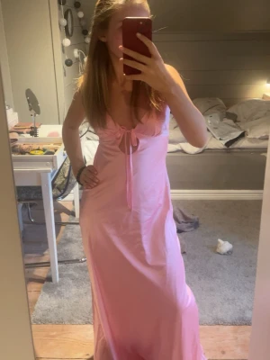 Rosa balklänning (xs) - Snygg rosa långklänning med knyt fram och även i rygg. Klänningen har en feminin passform och är ärmlös, perfekt för varma dagar. Mjuk och lätt i materialet, vilket gör den bekväm att bära. Klänningen är uppsydd så den passar på mig som är 160cm lång. Priset kommer inte sänkas då jag köpte den för 1200kr. Skriv vid frågor💞