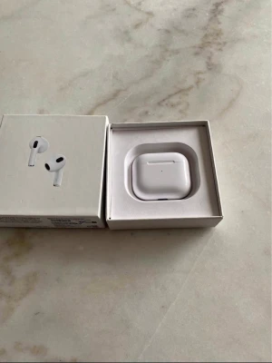 Apple AirPods 3 med laddningsetui - Säljer ett par vita Apple AirPods Pro med trådlöst laddningsetui. Hörlurarna har en stilren och kompakt design med silikonproppar för extra komfort. Perfekta för musik, samtal och träning tack vare brusreducering och smidig anslutning till iPhone.