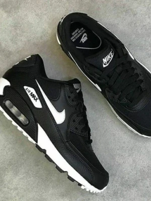 Nike Air Max 90 svart/vit sneakers - Säljer ett par klassiska Nike Air Max 90 sneakers i svart och vitt. Skorna har en chunky sula med synlig Air-enhet, vit swoosh på sidan och detaljer i både mesh och skinn. Perfekta för dig som vill ha en ikonisk och stilren look.