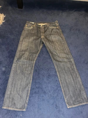 Levi's 501 jeans   - Klassiska Levi's 501 jeans i mörkblå denim med raka ben och normal passform. Byxorna har fem fickor, knappgylf och kontrastsömmar. Perfekta för dig som gillar tidlös stil och vill ha ett par ikoniska jeans i garderoben. Hör av dig om du vill ha bild på hur de ser ut på - är dock lite för stora för mig:)