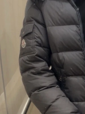 Svart dunjacka från Moncler - Säljer en svart dunjacka från Moncler med quiltad design och Moncler-logga på ärmen. Jackan har lång ärm, dragkedja framtill och en klassisk pufferlook som håller dig varm under kalla dagar.
