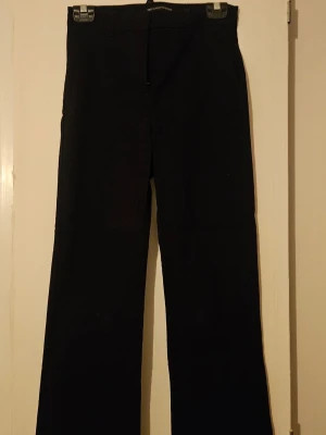 Svarta kostymbyxor med raka ben - Stilrena svarta kostymbyxor med klassisk rak passform och diskreta fickor bak. Byxorna är lite mindre, typ petite storlek.