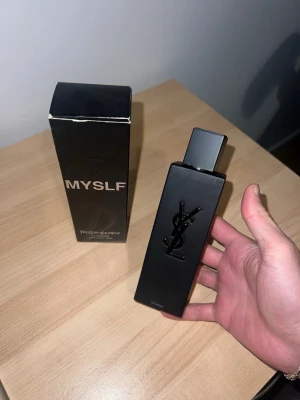 Yves Saint Laurent MYSLF parfym - Snygg parfym från Yves Saint Laurent, MYSLF, i en matt svart rektangulär flaska med YSL-logga i relief på framsidan. Flaskan har en stilren och modern design med svart plastlock. Kommer med originalkartong.Använt väldigt lite , runt 80ml kvar !! 