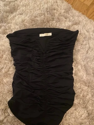 Body från Zara  - Säljer en svart body från Zara i storlek S. Toppen är axelbandslös och har snygga rynkade detaljer framtill som ger en cool och trendig look. Enadst testad. Lappen är inte kvar. 