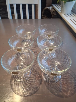 glasskålar/dessertskålar på fot Luminarc France - Säljer ett set med sex genomskinliga glasskålar/dessertskålar på fot från Luminarc. Skålarna har en elegant räfflad design och är perfekta för dessert eller glass. Tillverkade i glas och har en klassisk rund form med en liten fot för extra stabilitet. Ena glaset saknar klistermärke ä, står France I botten på alla. Höjd 9.5cm Diameter 11.5cm.  Ett glas väger 270 gram 