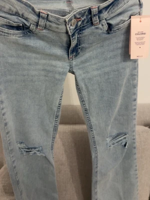 Low waist nelly jeans - Oanvända lågmidjade jeans från nelly med slits vid knäna på varje sida i strl 36, prislappen är kvar.