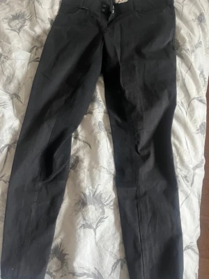 Mörkblåa ridbyxor från Back 2 Back - Säljer ett par svarta ridbyxor från Back 2 Back i storlek 42. Byxorna har kardborre längst ner på benen så du kan justera hur hårt/löst du vill de ska sitta. Halvskodda