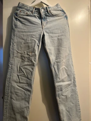 Ljusblåa lågmidjade straight jeans  - Ljusblåa jeans med rak passform och fem fickor. Jeansen har en tidlös look med knappgylf och är tillverkade i slitstark bomullsdenim. Perfekta för dig som gillar en avslappnad och autentisk stil.