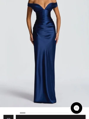 Marinblå offshoulder långklänning - Säljer en elegant marinblå långklänning i glansigt material med offshoulder och djup v-ringning. Klänningen har figurnära passform och markerad midja som ger en snygg siluett. Perfekt för bal eller festliga tillfällen. Klänningen är från baby boo, den har en inbyggt korsett som går att dra åt, säljer då de inte går att skicka tillbaka och jag hittat en annan klänning💗