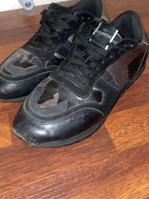 Valentino Rockrunner sneakers svart/camo - Snygga Valentino Rockrunner sneakers i svart med kamouflagemönster. Skorna har svarta snören, rund tå och detaljer i både skinn och mocka. Säljer pågrund av att dom inte passar mig längre 