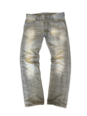 Grå Diesel jeans med slitningar  - Säljer ett par gråa Diesel Larkee jeans med straight fit och slitna detaljer. Jeansen har klassisk femficksdesign, normal midja och är tillverkade i mjukt jeansmaterial. Snyggt tvättade för en avslappnad look och passar perfekt till sneakers.