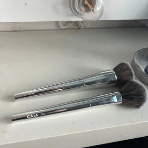 CAIA sminkborstar  - Två snygga sminkborstar från CAIA med silvriga handtag. F03 och foundation borsten! Jättefint skick, säljer då jag inte använder dem, skriv vid frågor💕