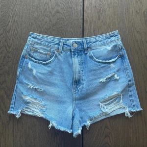Blå slitna jeansshorts Stradivarius - Snygga blå jeansshorts från Stradivarius i klassisk femficksmodell. Shortsen är midrise med slitna detaljer och fransig kant nedtill för en cool, avslappnad vibe. 