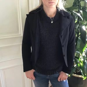 Svart kavaj från Bröderna Magnusson - Stilren svart kavaj med klassisk krage och knäppning framtill från Bröderna Magnusson Borås. Jackan har en figurnära passform och är helfärgad utan mönster. Perfekt att slänga på sig över en stickad tröja för en snygg look.